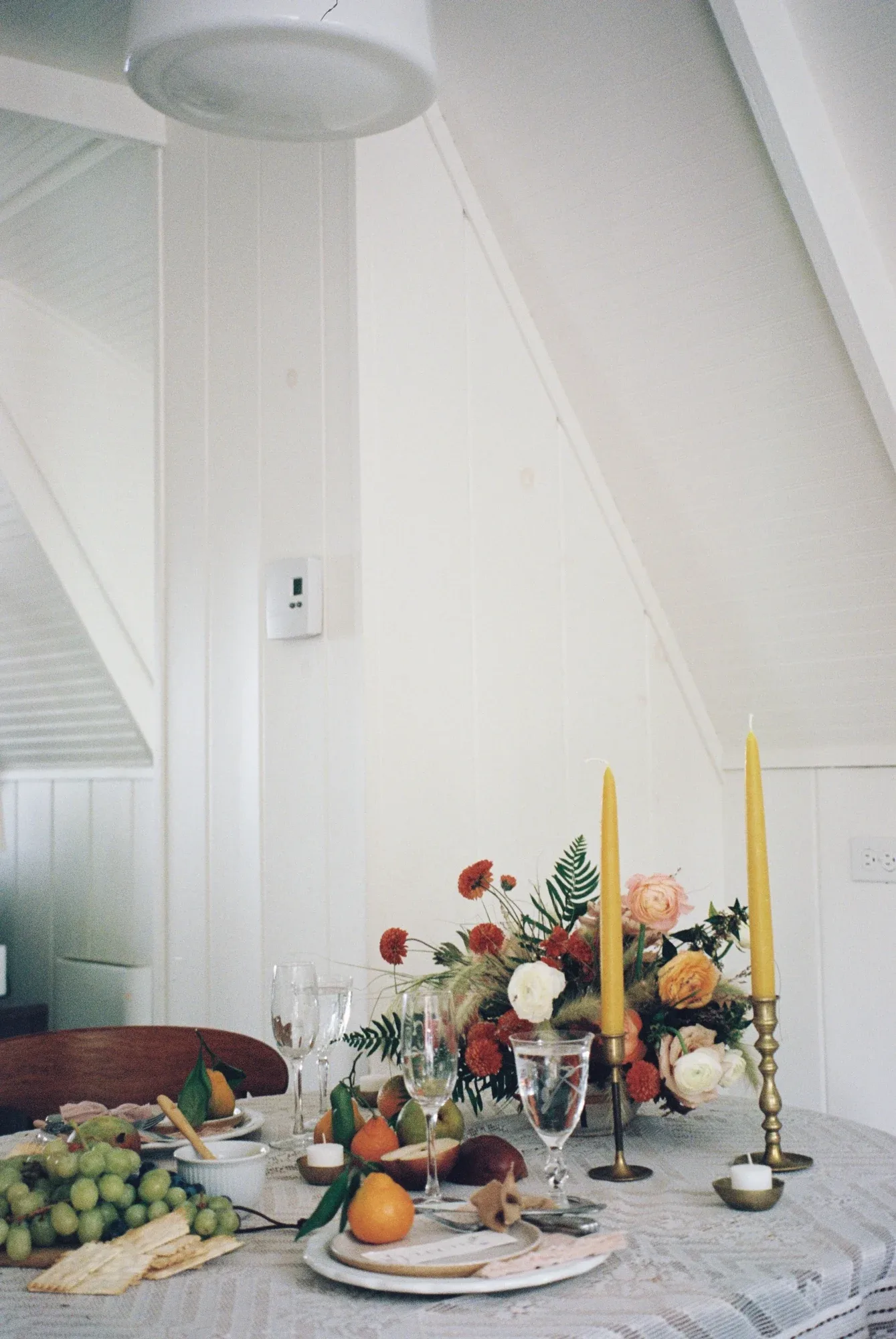 Taper candles and a fruit-laden table inside a white A-frame